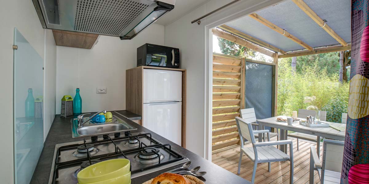 Equipped kitchen with view on the terrace of the Déclik 32 mobile home at Le Fief campsite