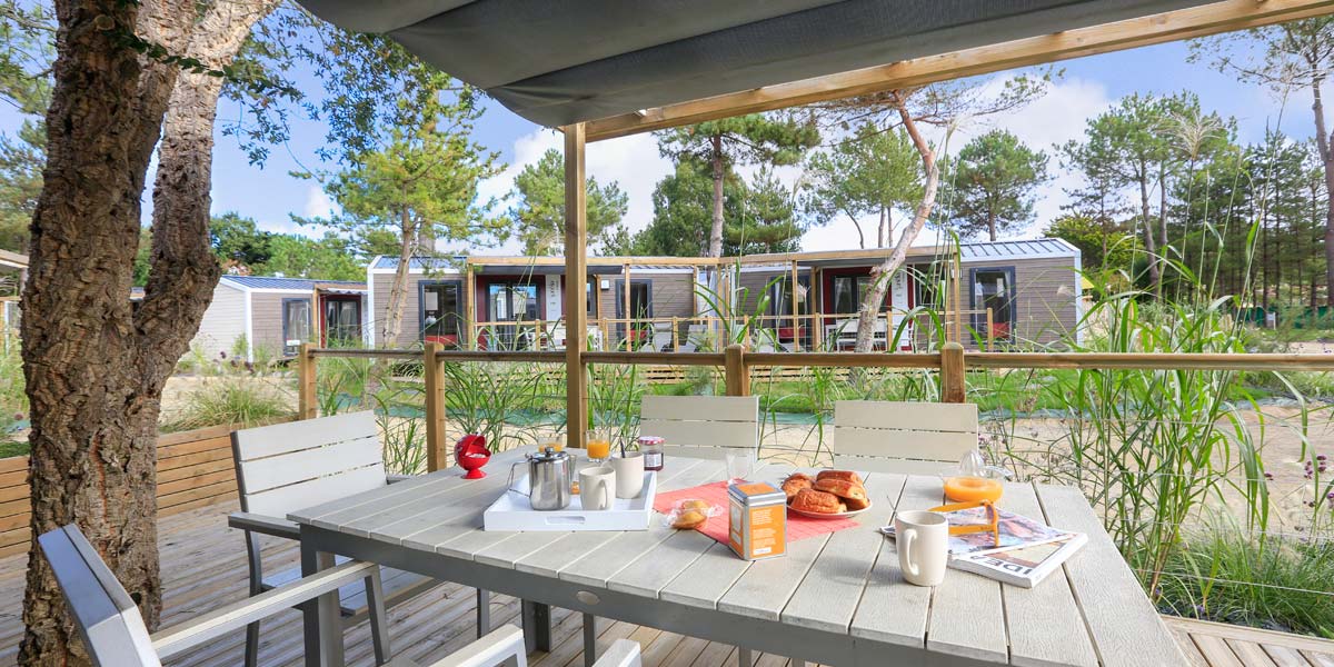 Blick auf die Terrasse mit Tisch vom Premium 32 Mobilheim auf dem Campingplatz Le Fief