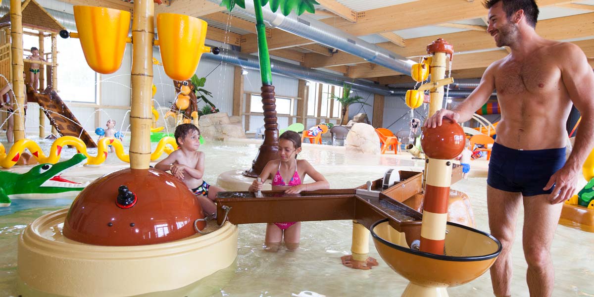 Ein Vater und seine Kinder auf dem Spielplatz des Wasserparks auf dem Campingplatz Le Fief