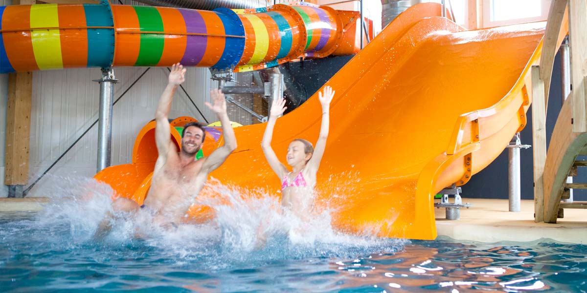 Waterglijbanen in de overdekte en verwarmde ruimte van het waterpark van camping Le Fief