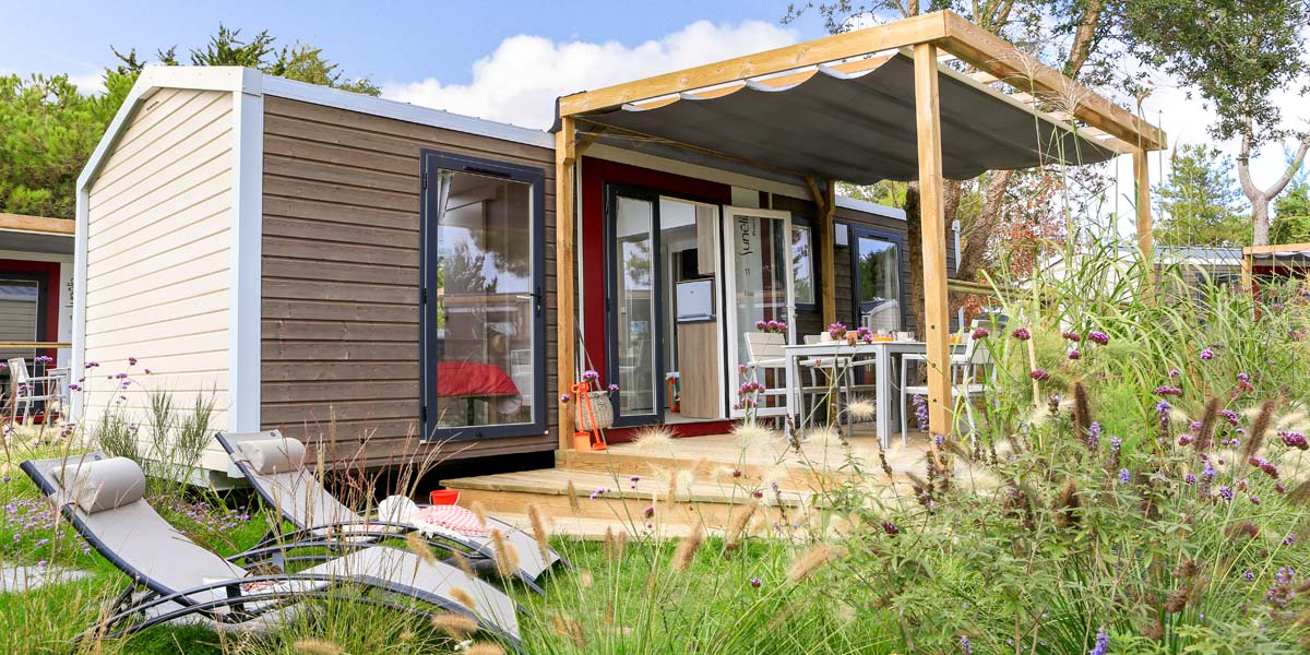 Liegestuhl und halb überdachte Holzterrasse des Mobilheims Premium 32 auf dem Campingplatz Le Fief