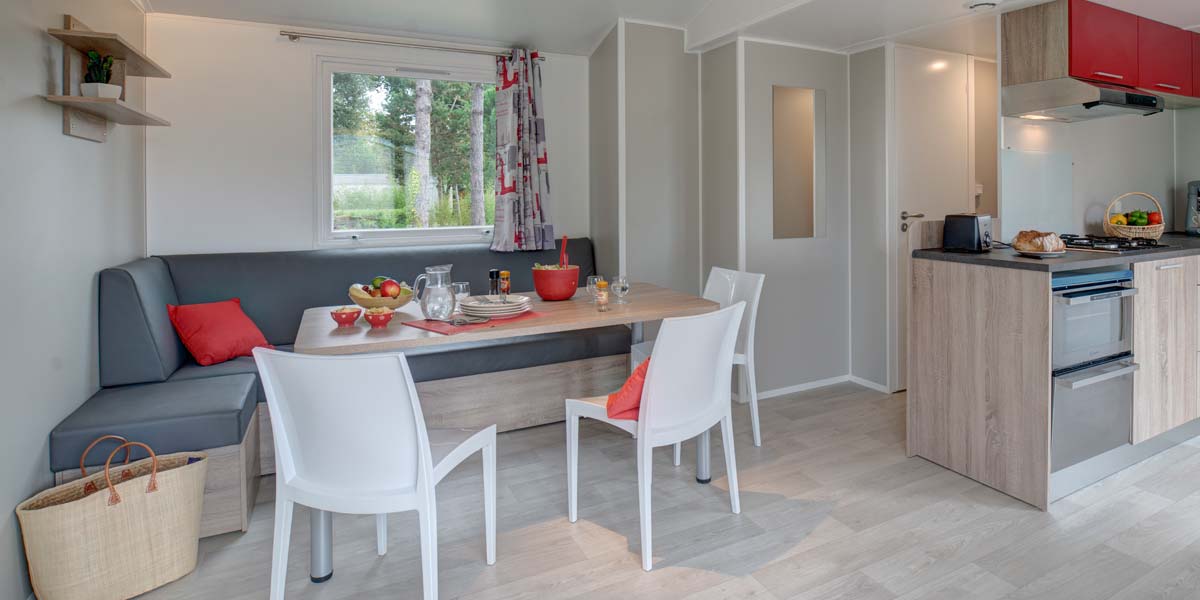 Lounge area with bench seat and table of the Premium 40 mobile home at Le Fief campsite