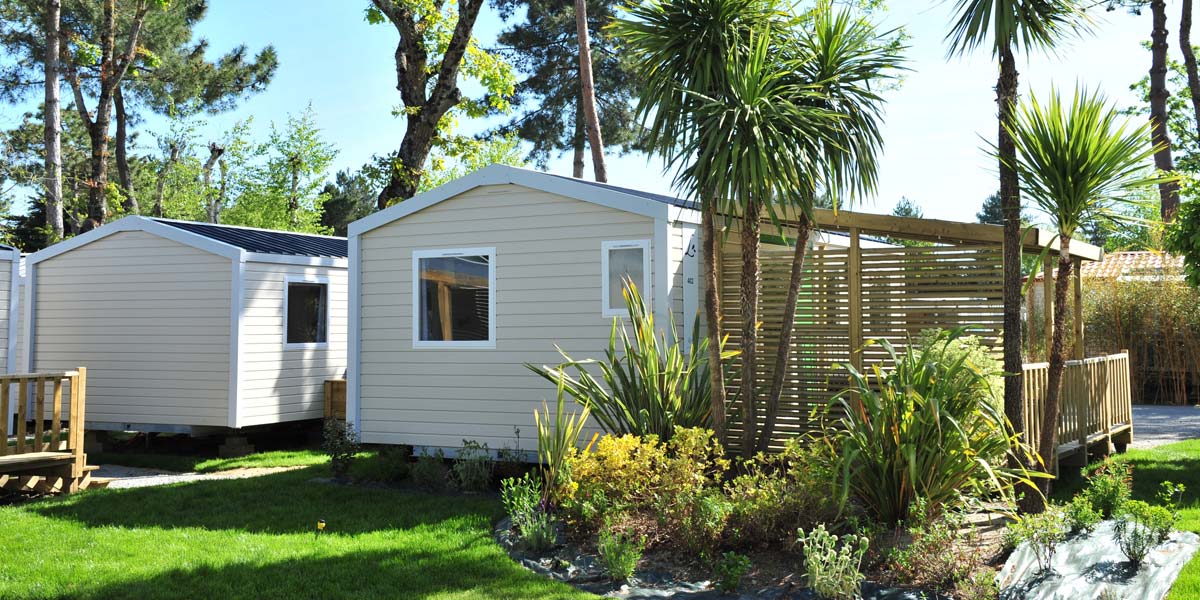 Massive vegetation in front of a mobile home with terrace at Le Fief campsite