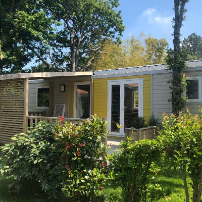 Hedge and facade of a comfortable mobile home at Le Fief campsite in Saint-Brevin