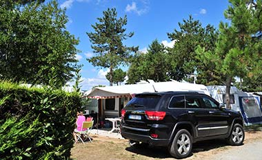 Car and caravan on pitch bordered by hedges at Le Fief campsite in Saint-Brevin
