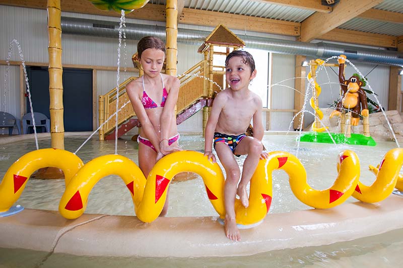 Kinder spielen mit Wasserstrahlen im Wasserpark auf dem Campingplatz Le Fief